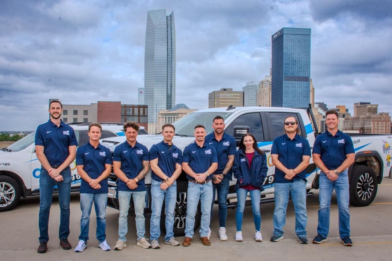 OKC Roofers sales and inspection team in front of company trucks with the downtown Oklahoma City skyline in the background