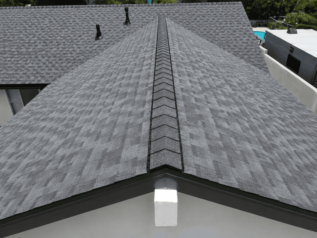 A close-up view of a gray asphalt shingle roof showing the ridge cap