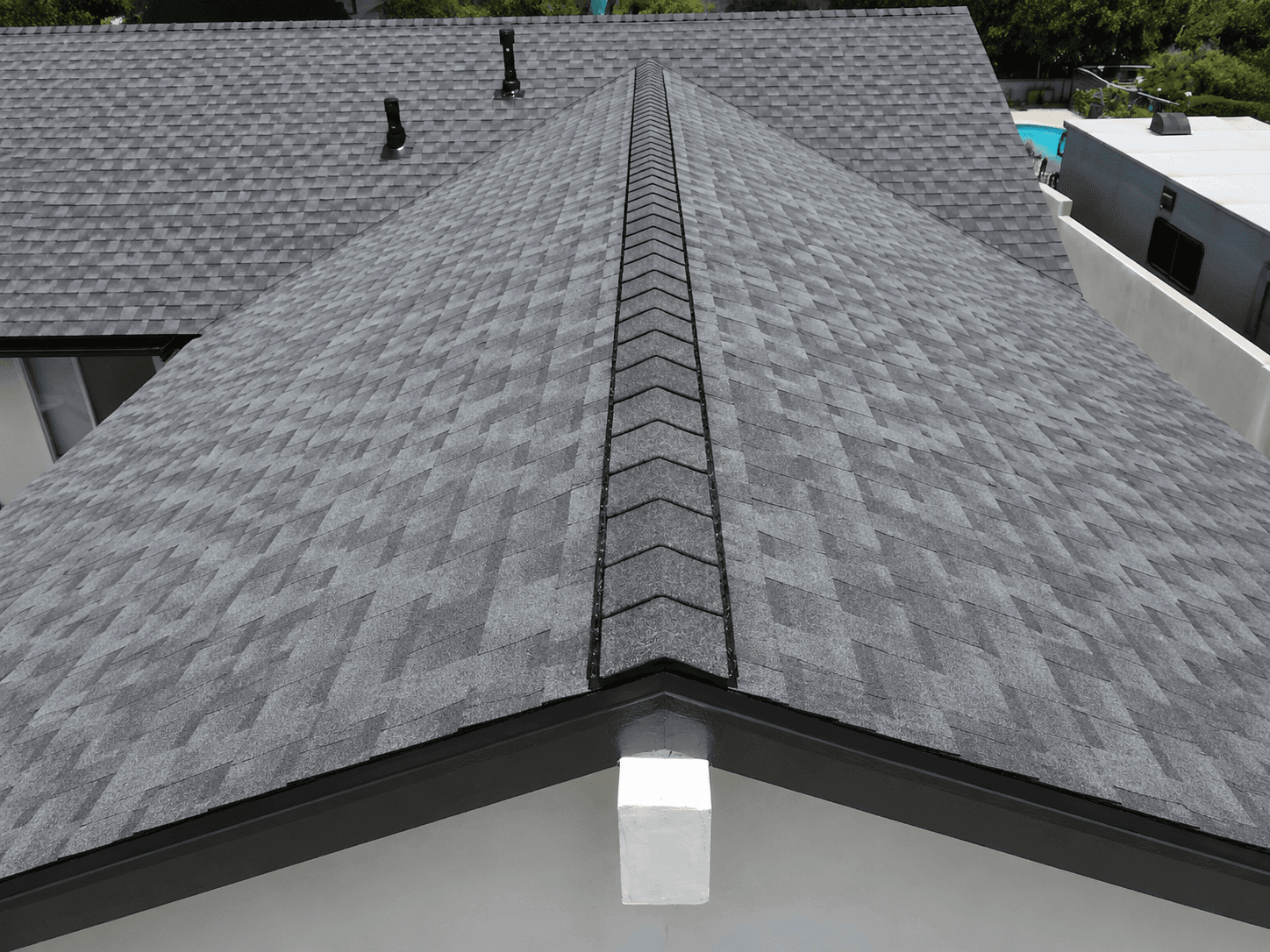 A close-up view of a gray asphalt shingle roof showing the ridge cap
